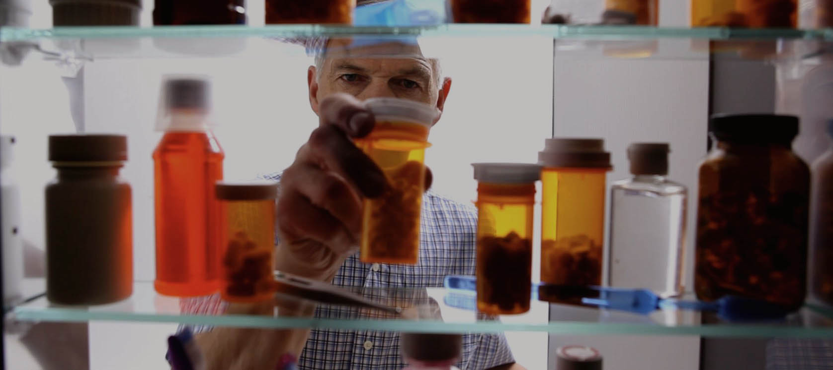 Old man taking pills bottle from shelf